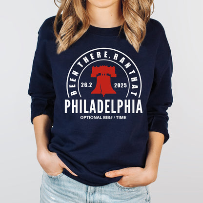 Person wearing a navy blue sweatshirt with Philadelphia marathon design on a light gray background